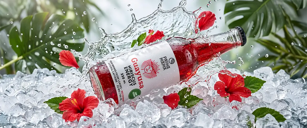 En flaska Guayusa Pachamama Cold Brew på krossad is med hibiskusblommor.